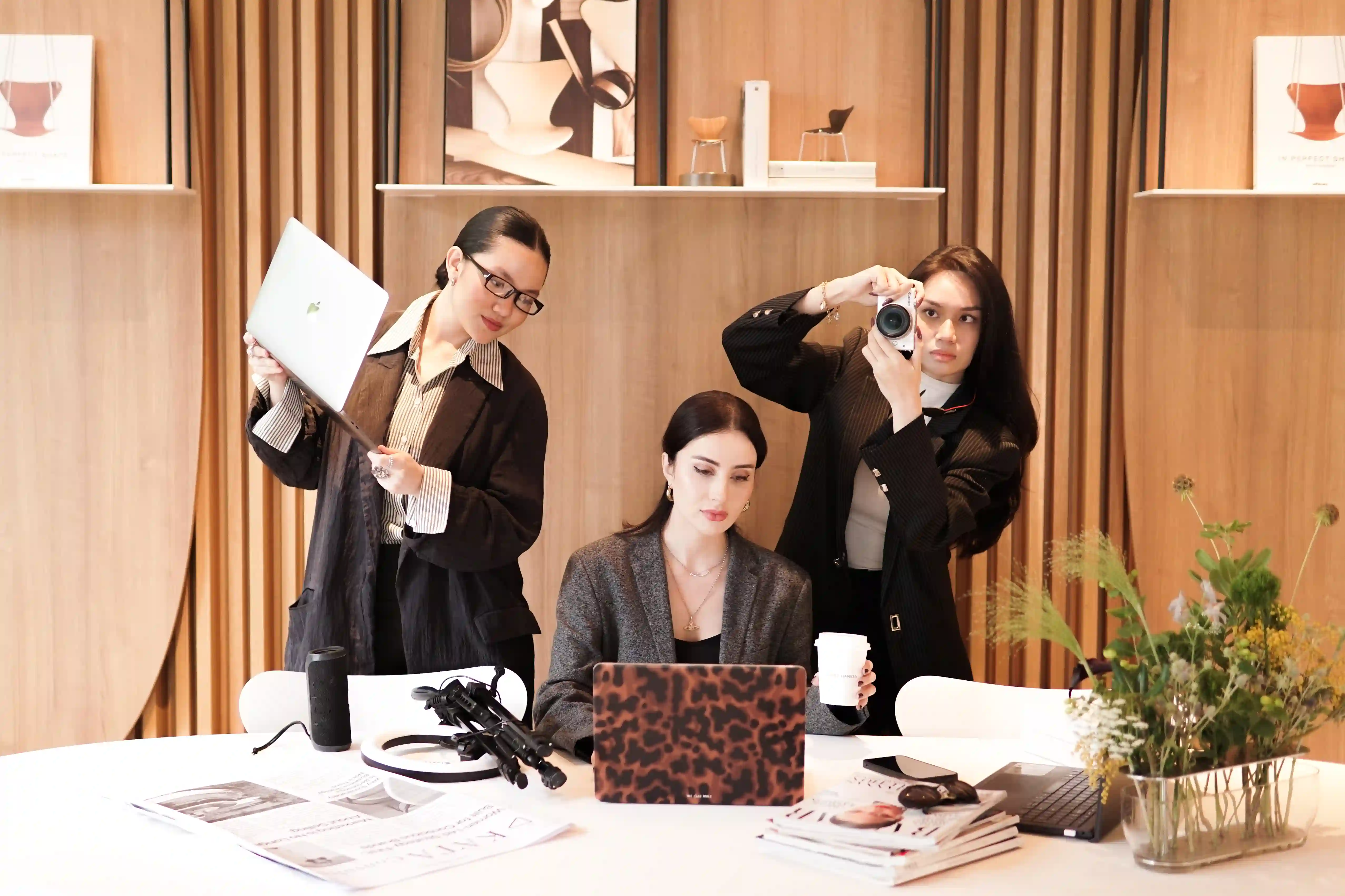 KATA team reviewing a mock magazine spread with Vogue and Harper's Bazaar issues on the table
